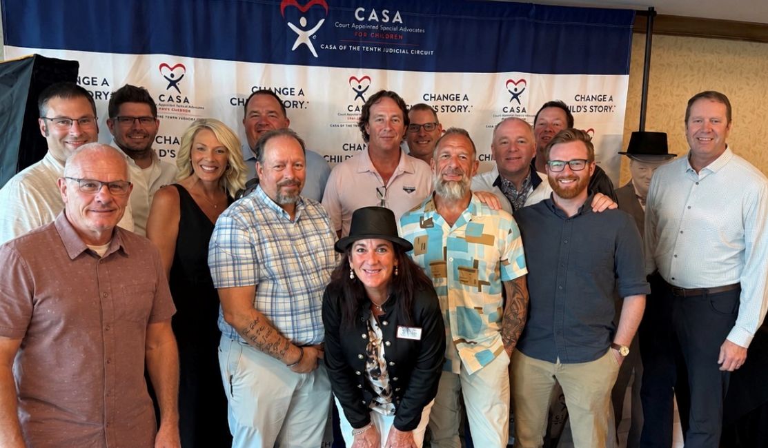 Stratus Networks team gathered in front of the CASA - Court Approved Special Advocates banner