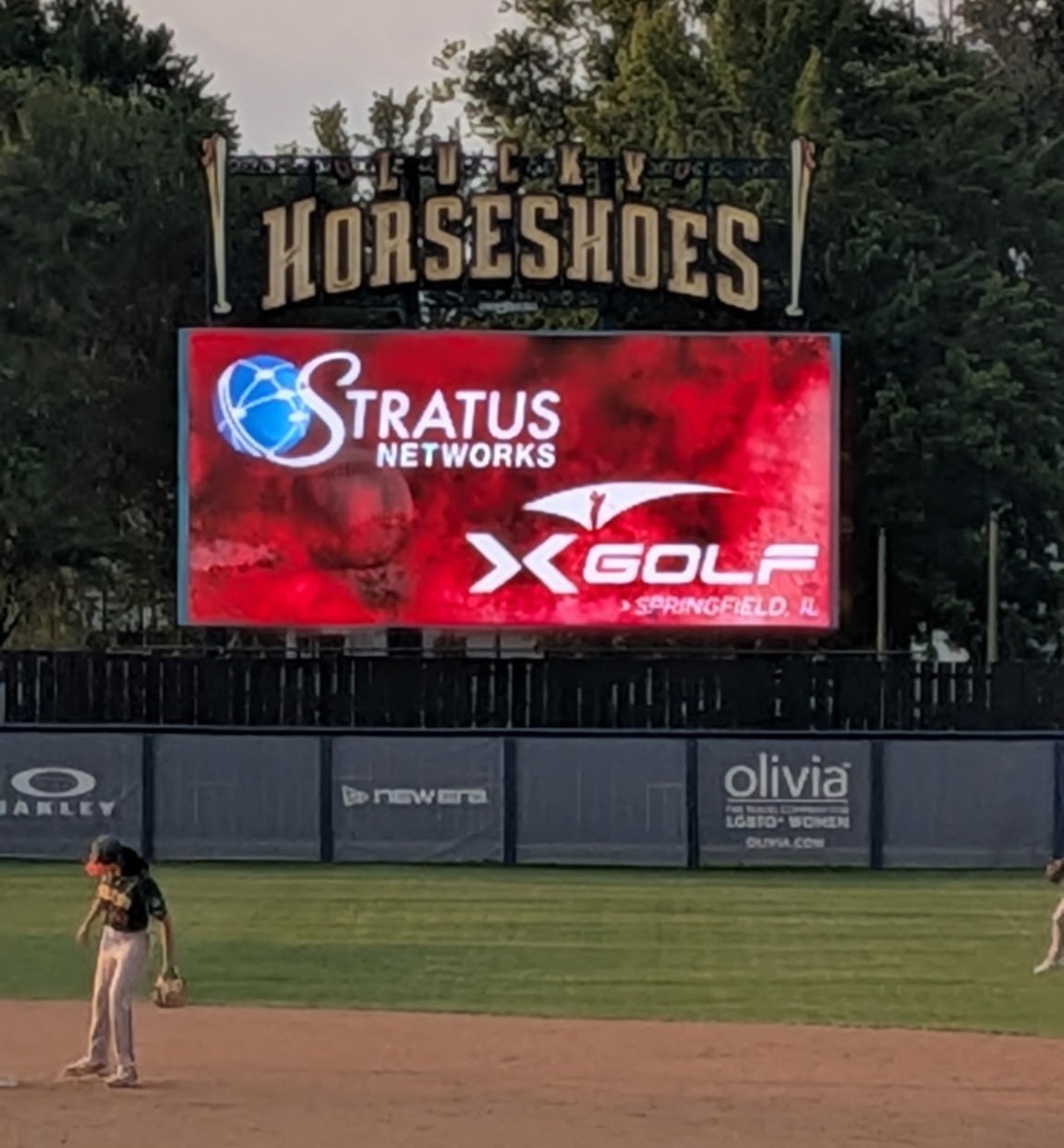 Stratus Networks appearing on a sponsor's billboard for women's baseball team the Lucky Horseshoes