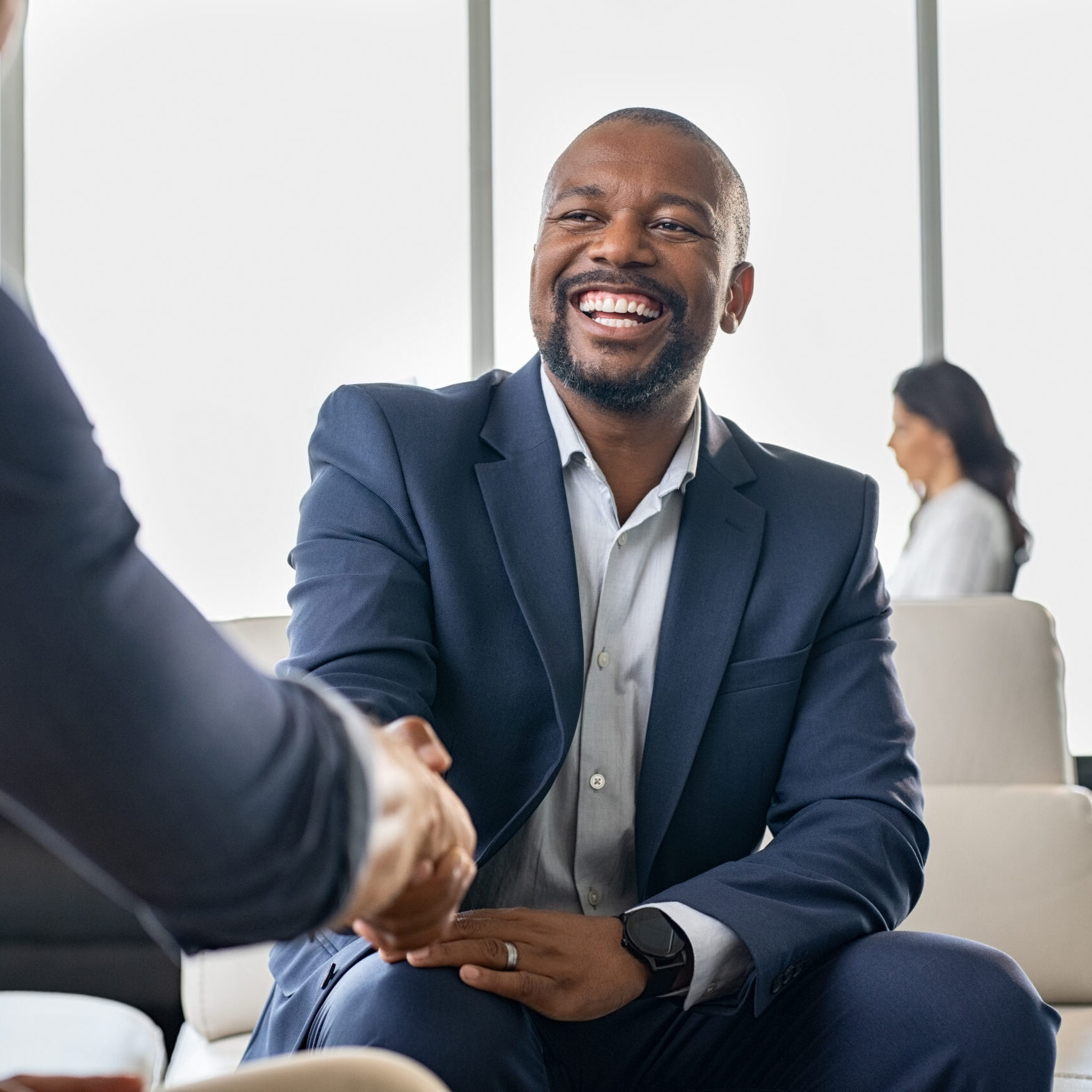 Two happy mature business men shaking hands in modern office. Successful african american businessman in formal clothing closing deal with handshake. Multiethnic businessmen shaking hands during a meeting.
